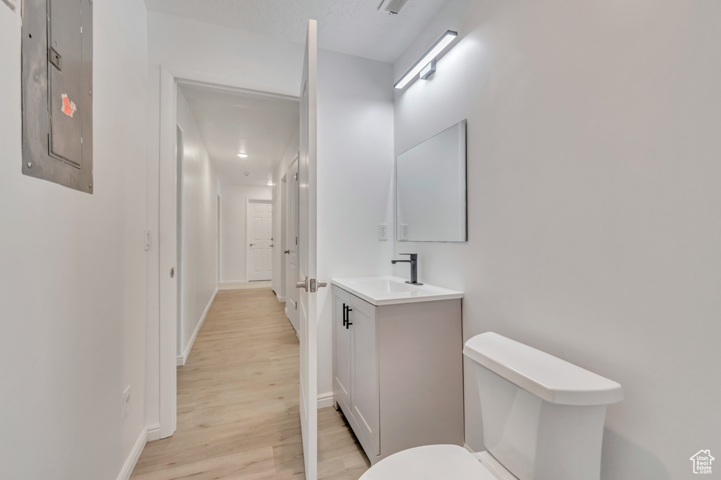 Bathroom with vanity, toilet, hardwood / wood-style floors, and electric panel