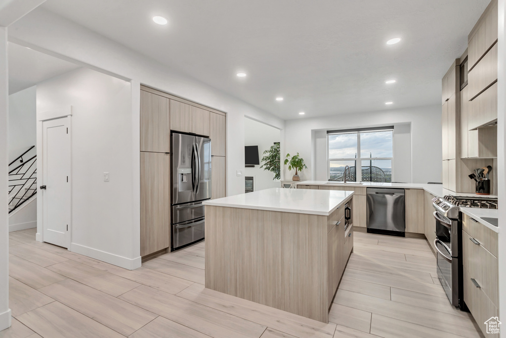 Kitchen featuring sink, appliances with stainless steel finishes, a kitchen island, and light brown cabinets