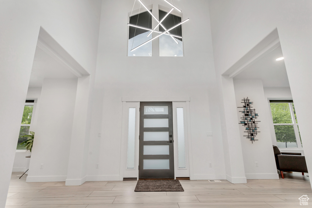 Entrance foyer with light hardwood / wood-style floors, plenty of natural light, and a towering ceiling