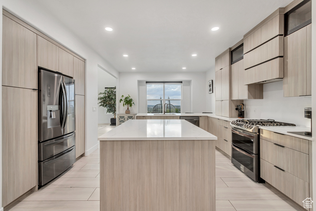 Kitchen featuring a center island, light brown cabinets, stainless steel appliances, sink, and light hardwood / wood-style floors