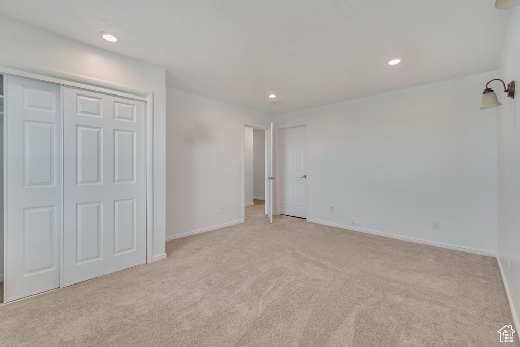 Unfurnished bedroom with a closet and light carpet