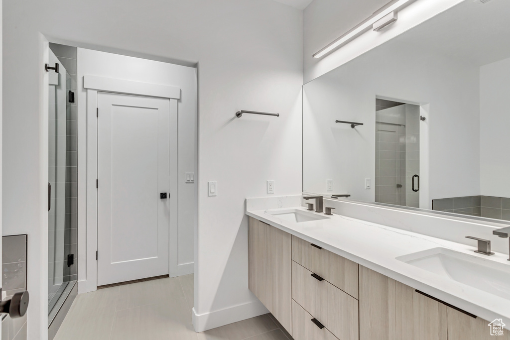 Bathroom featuring an enclosed shower, double vanity, and tile flooring