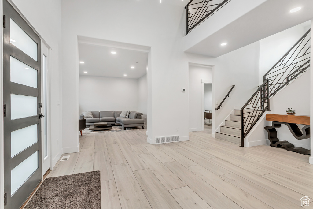 Foyer with a towering ceiling and light wood-type flooring