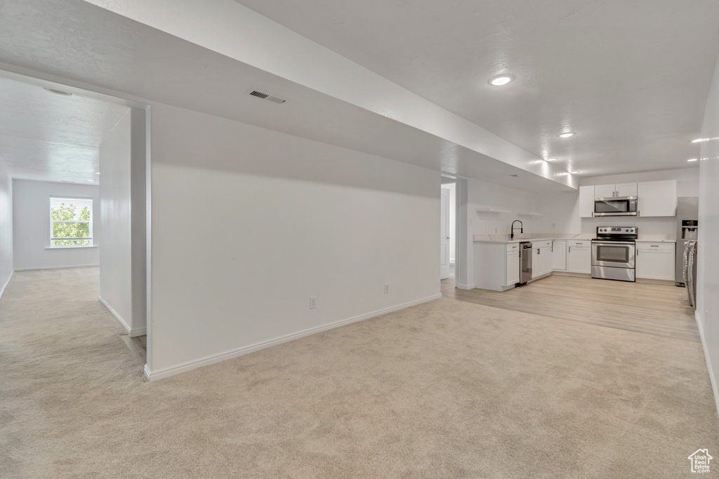 Unfurnished living room with sink and light carpet