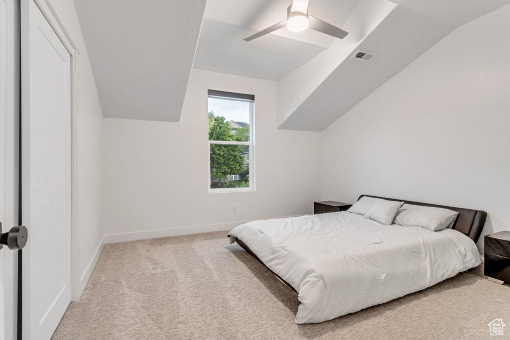 Carpeted bedroom featuring vaulted ceiling and ceiling fan