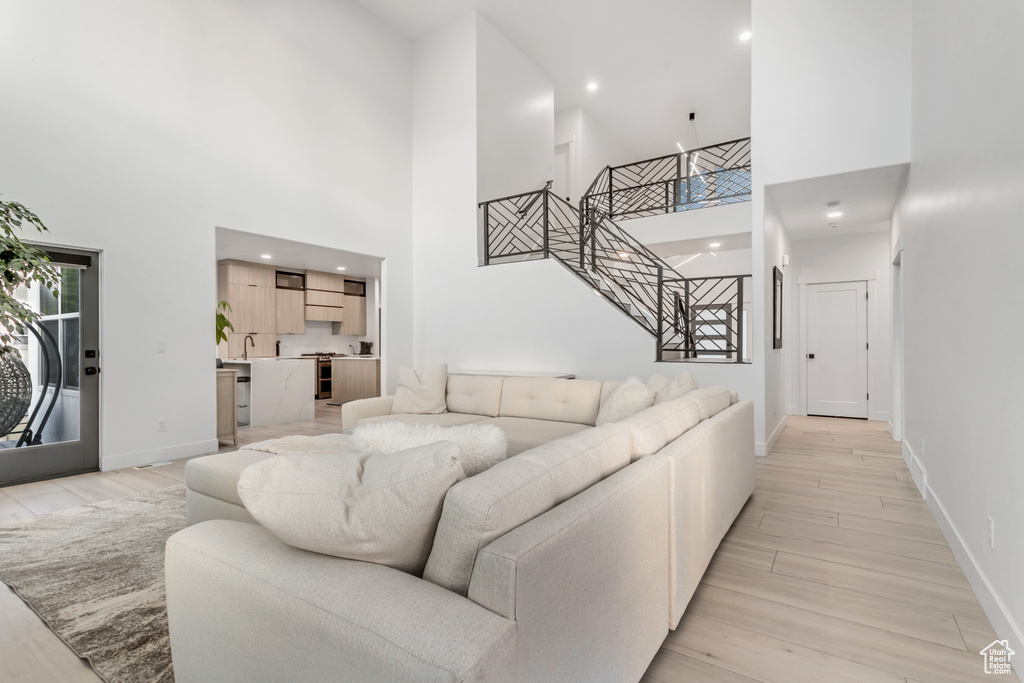 Living room with sink, a high ceiling, and light wood-type flooring