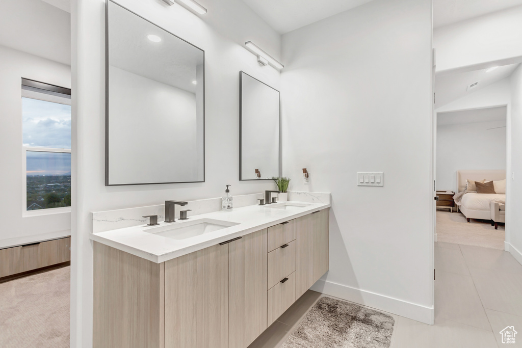 Bathroom with tile floors, vanity with extensive cabinet space, and dual sinks