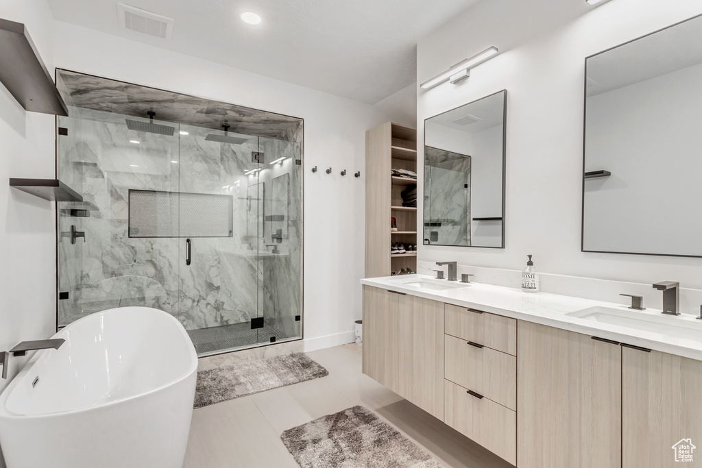 Bathroom with tile flooring, independent shower and bath, and double sink vanity