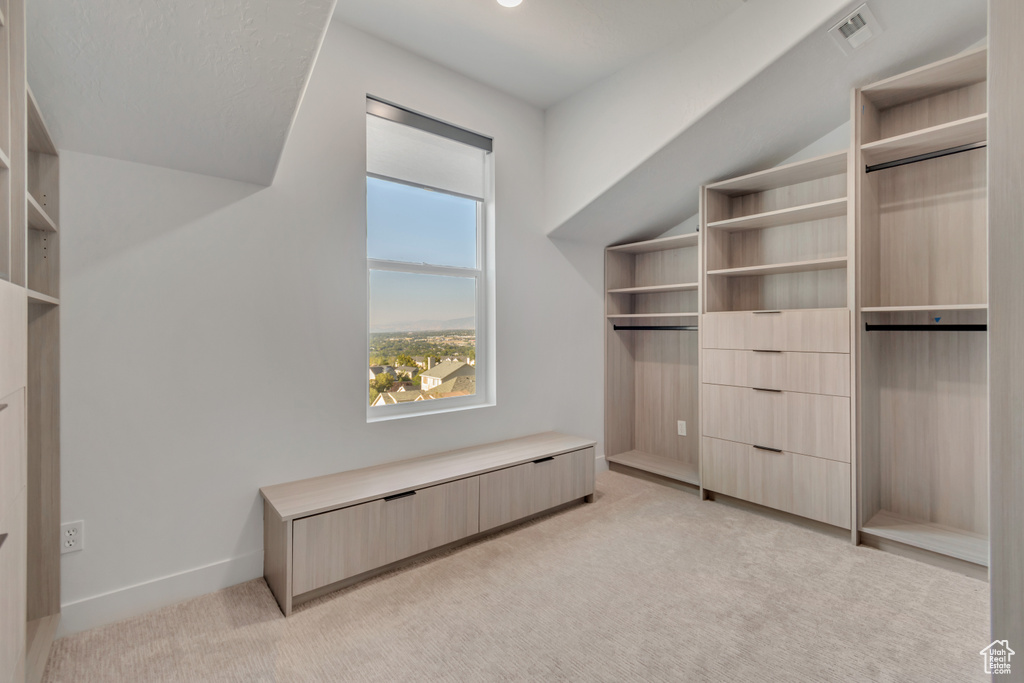 Walk in closet featuring lofted ceiling and light colored carpet