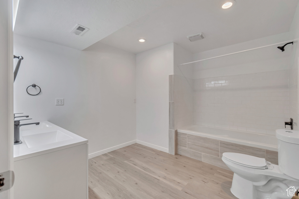 Full bathroom featuring tiled shower / bath, vanity, toilet, and wood-type flooring