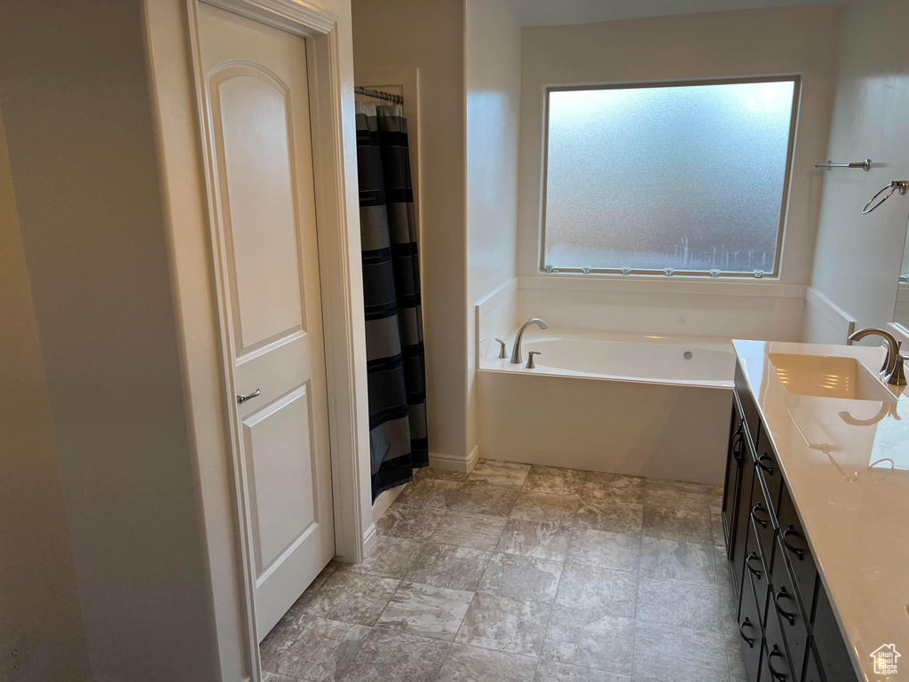 Bathroom featuring tile flooring, vanity, and a washtub