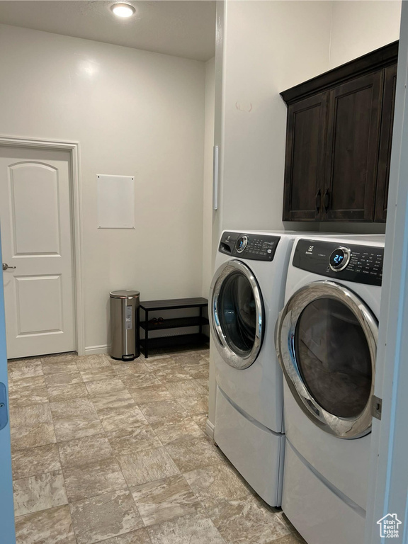 Washroom featuring cabinets, washing machine and dryer, and light tile floors