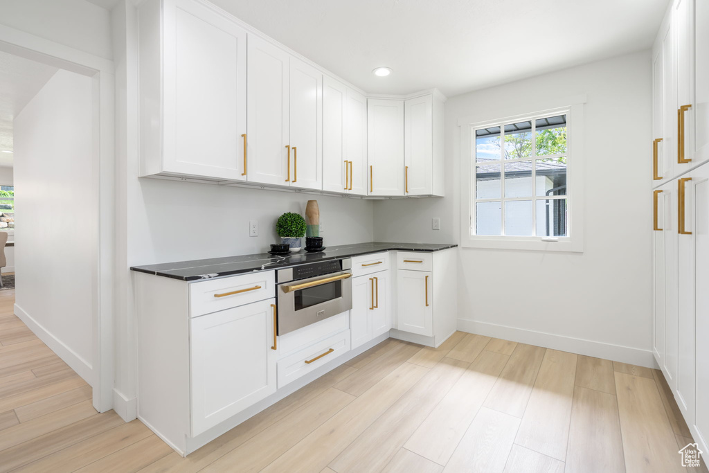 Kitchen with white cabinets, light wood-type flooring, and stainless steel oven