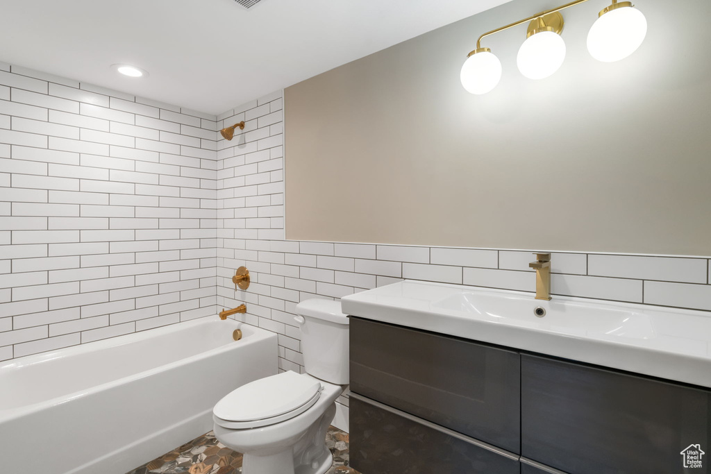 Full bathroom with tiled shower / bath, tile walls, vanity, tile flooring, and toilet