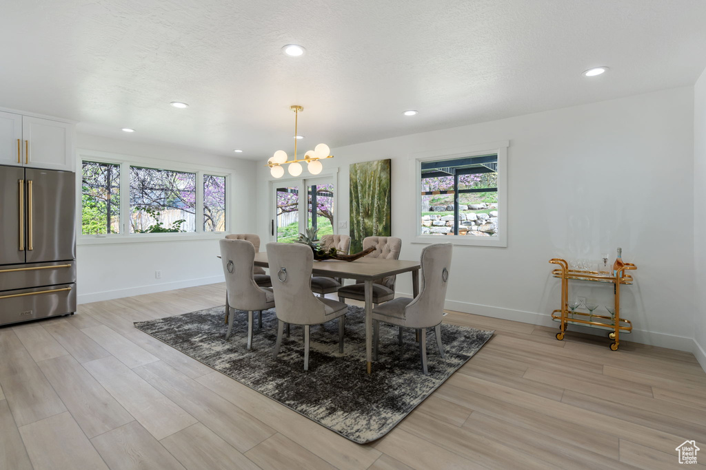 Dining space with light hardwood / wood-style floors and a chandelier