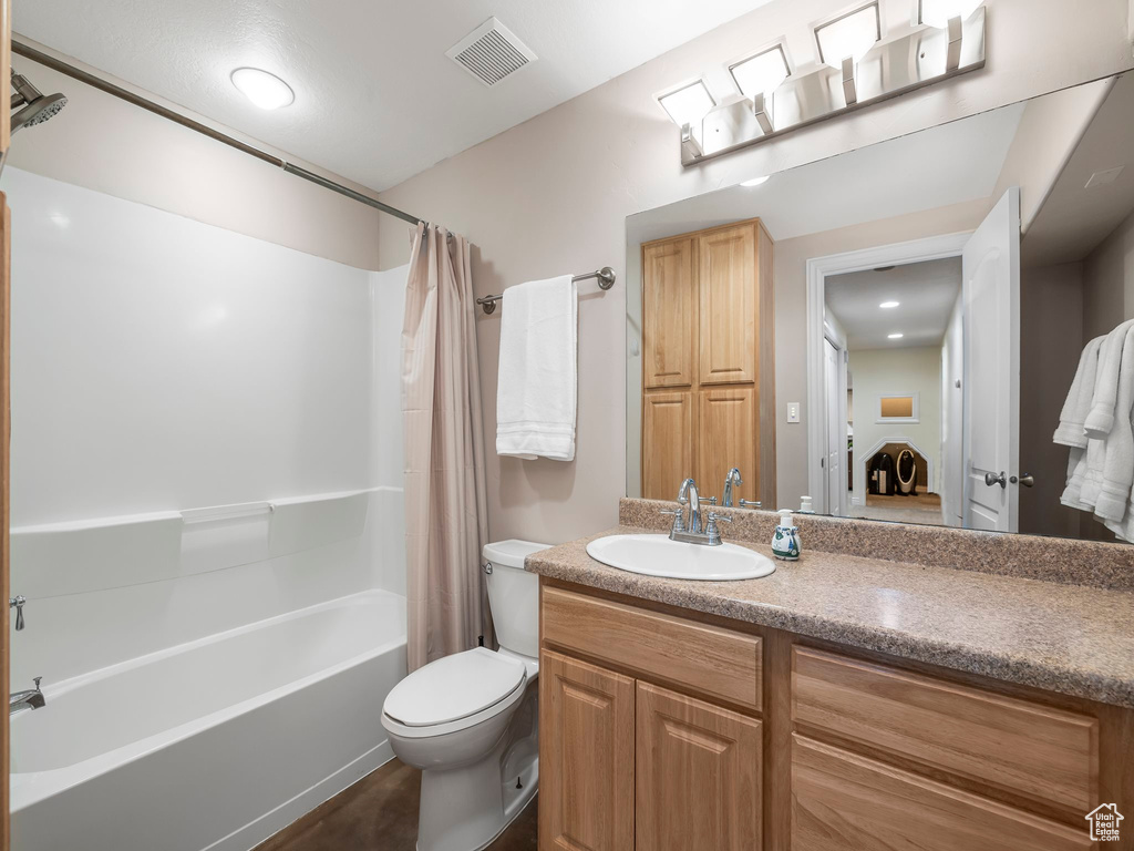 Full bathroom featuring vanity, shower / bathtub combination with curtain, and toilet