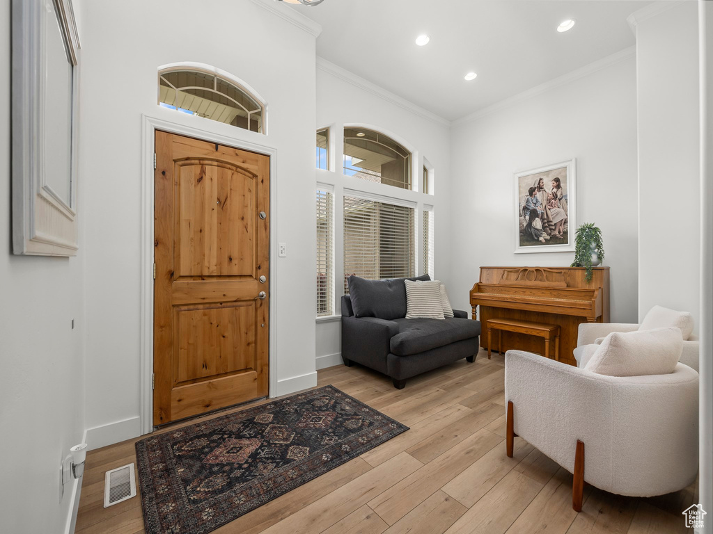 Entryway with light hardwood / wood-style flooring and crown molding