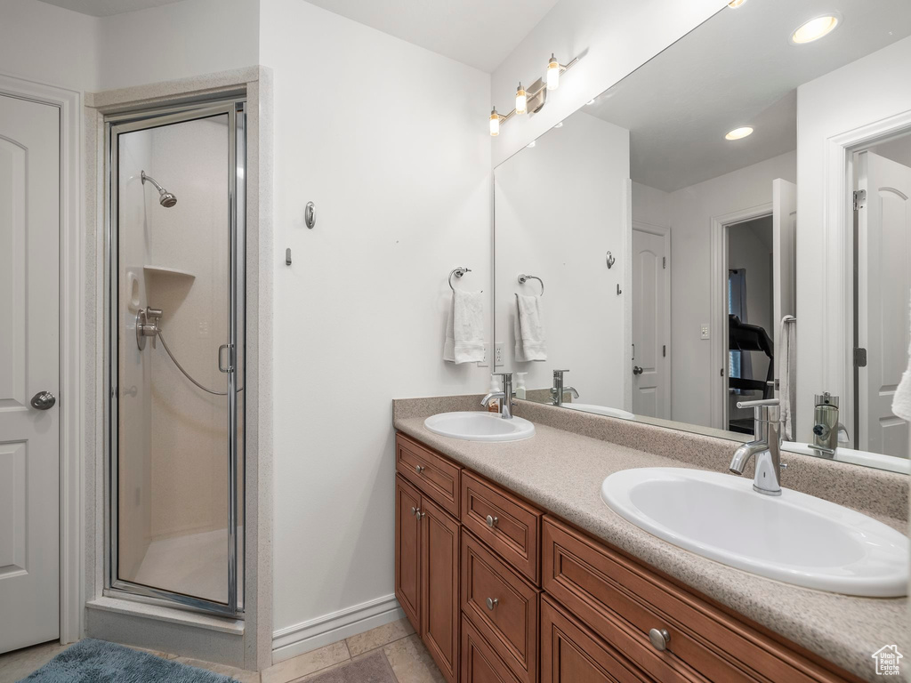 Bathroom featuring an enclosed shower, tile floors, and dual vanity
