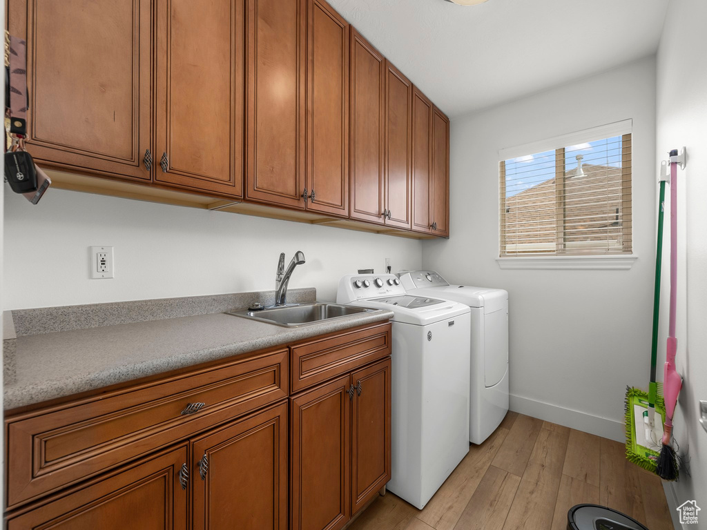 Laundry room featuring cabinets, light hardwood / wood-style floors, separate washer and dryer, and sink