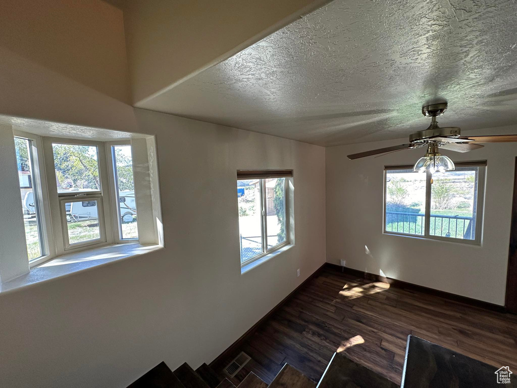 Empty room featuring ceiling fan, dark hardwood / wood-style floors, and a textured ceiling