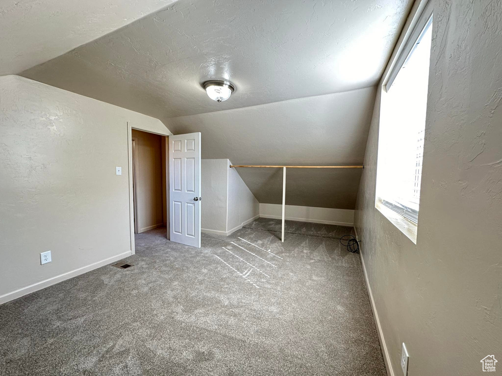 Additional living space featuring a textured ceiling, carpet floors, and lofted ceiling