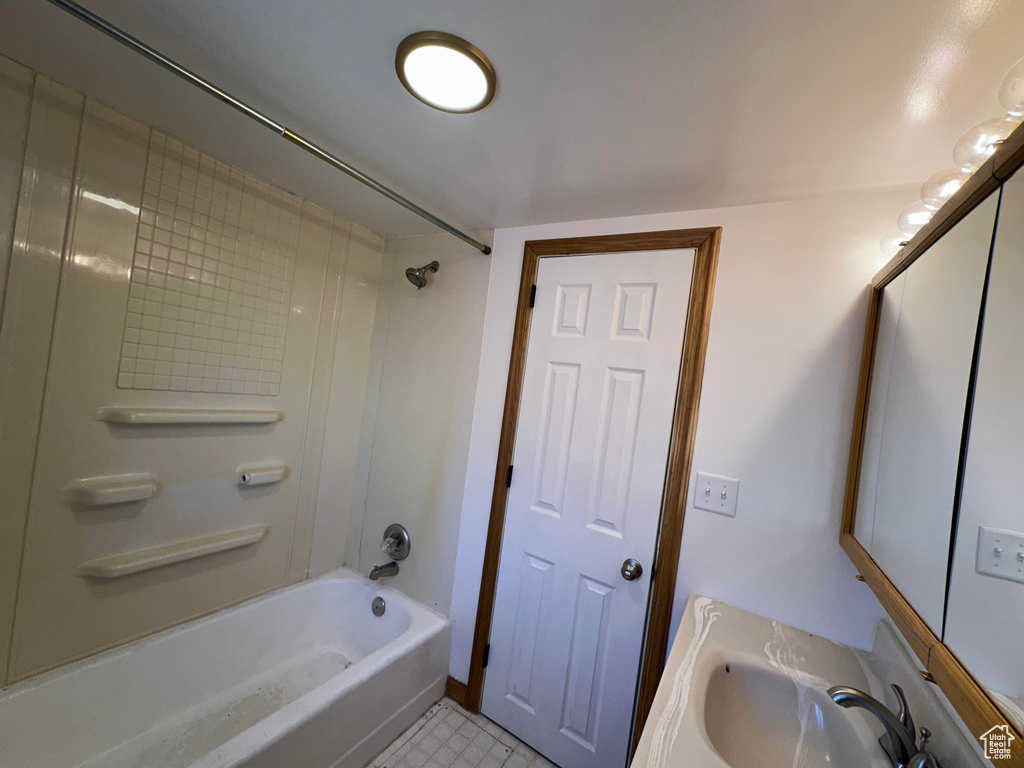 Bathroom with tiled shower / bath combo, tile floors, and vanity