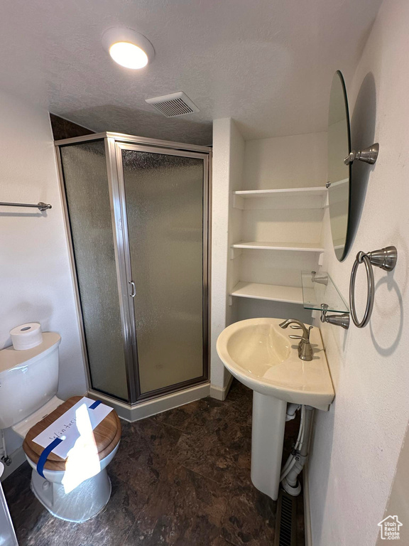 Bathroom featuring tile flooring, sink, toilet, and a shower with shower door
