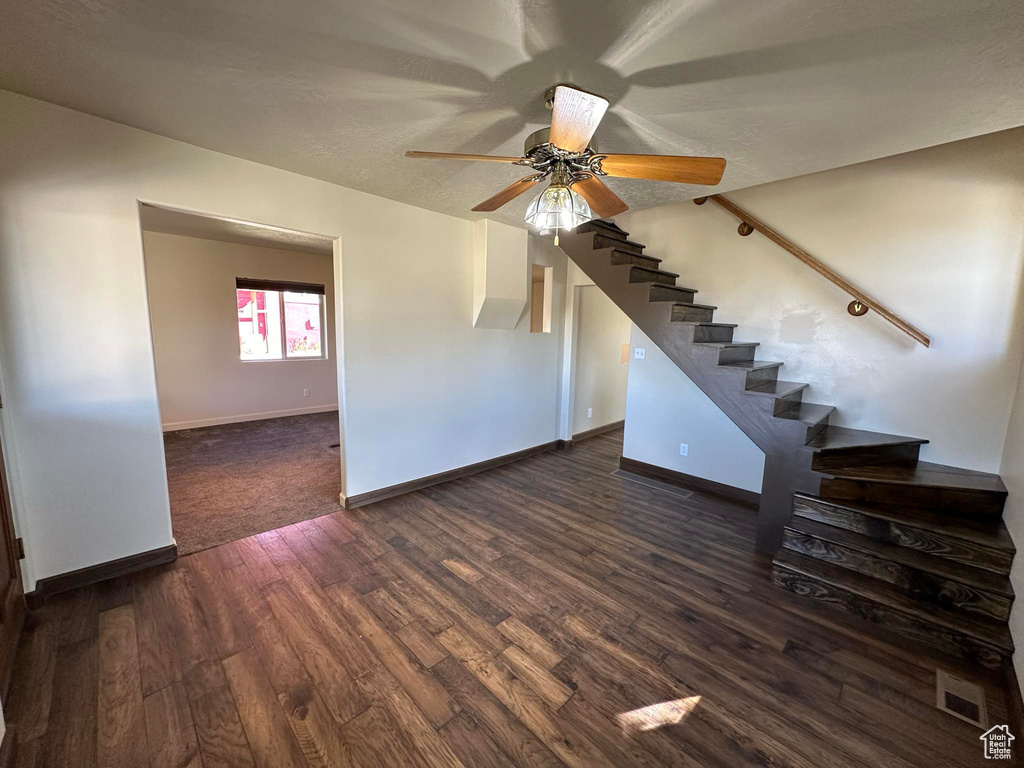 Unfurnished living room featuring dark hardwood / wood-style flooring and ceiling fan