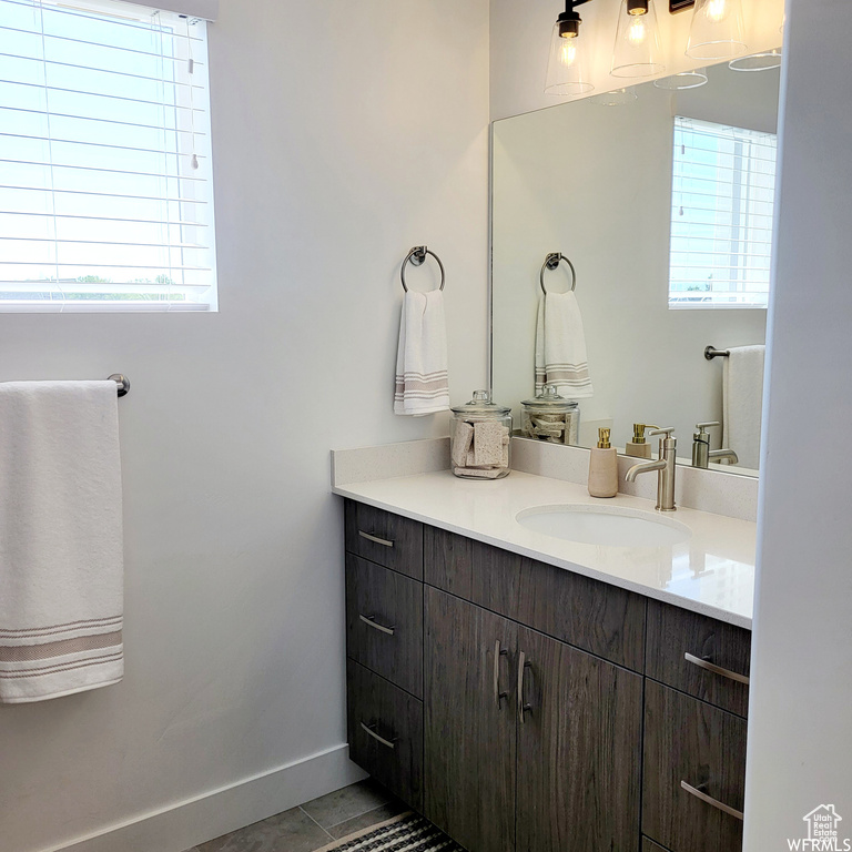 Bathroom featuring vanity with extensive cabinet space, a healthy amount of sunlight, and tile floors