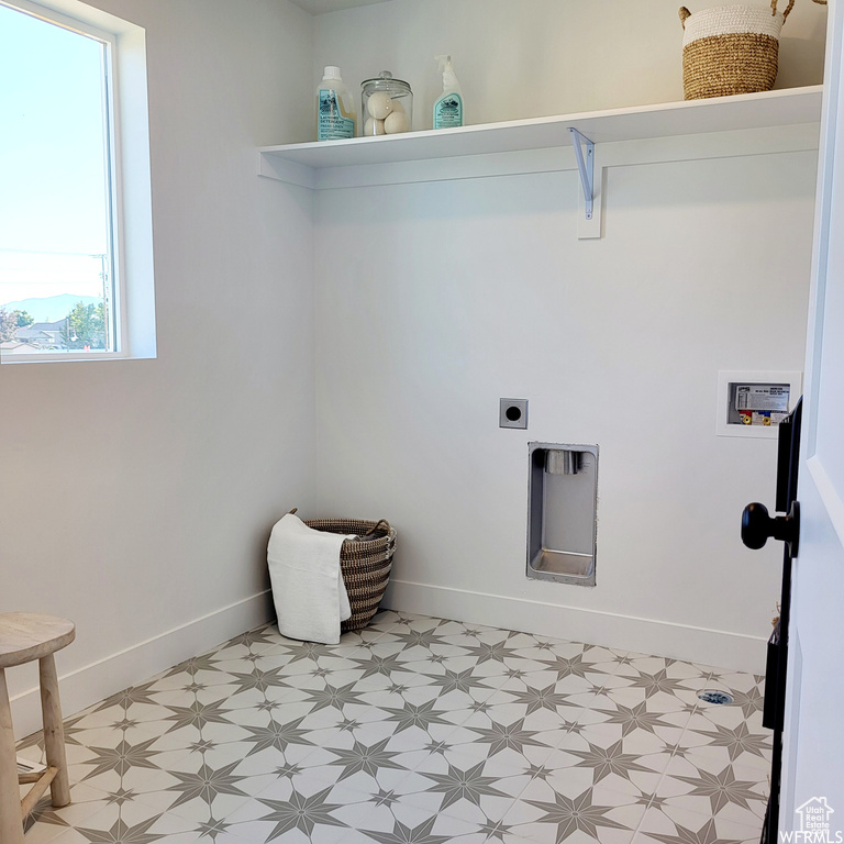 Laundry room featuring electric dryer hookup and light tile flooring