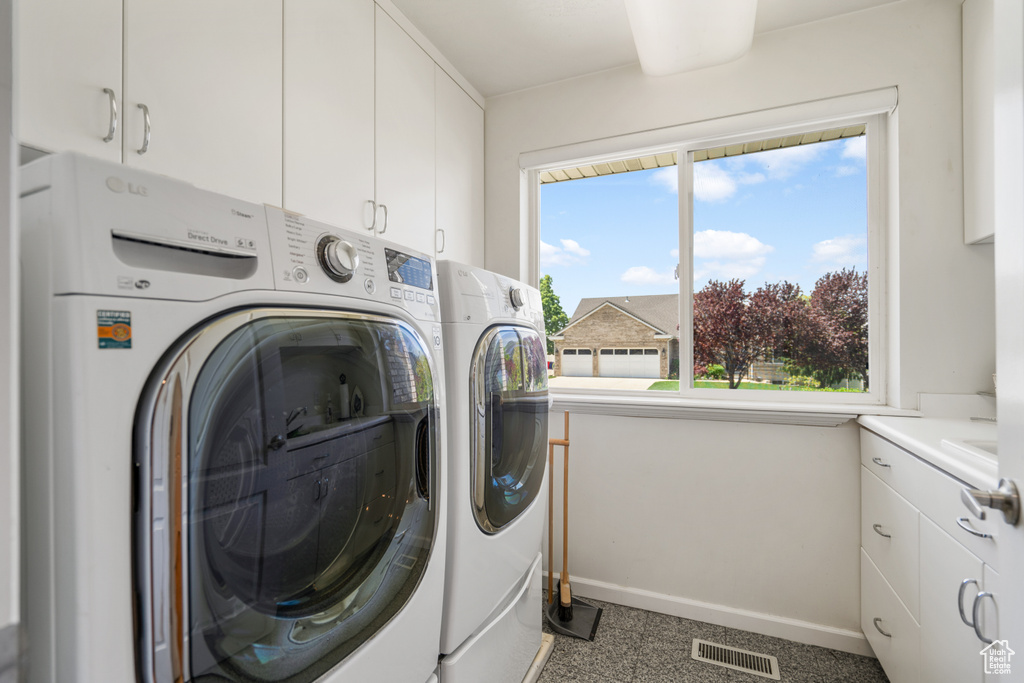 Laundry area featuring plenty of natural light, independent washer and dryer, and cabinets