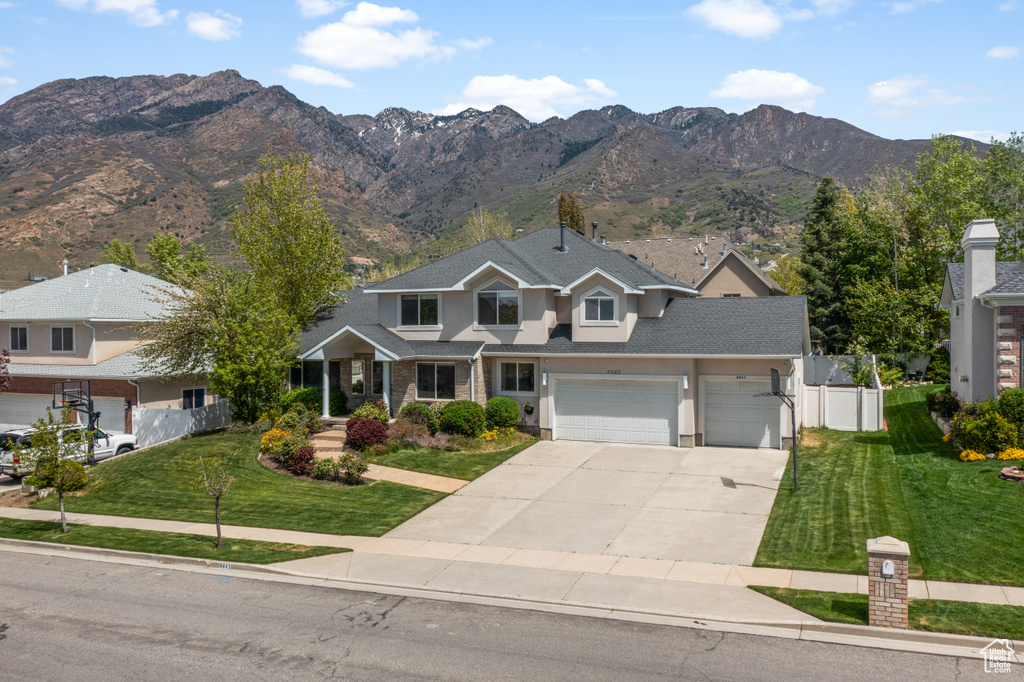 View of front of house with a mountain view, a front lawn, and a garage