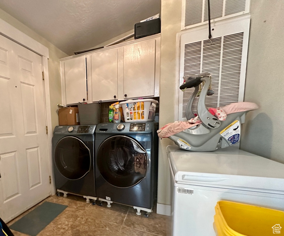 Washroom with washer and dryer, cabinets, and tile floors