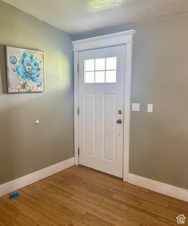 Doorway to outside with a textured ceiling and hardwood / wood-style floors