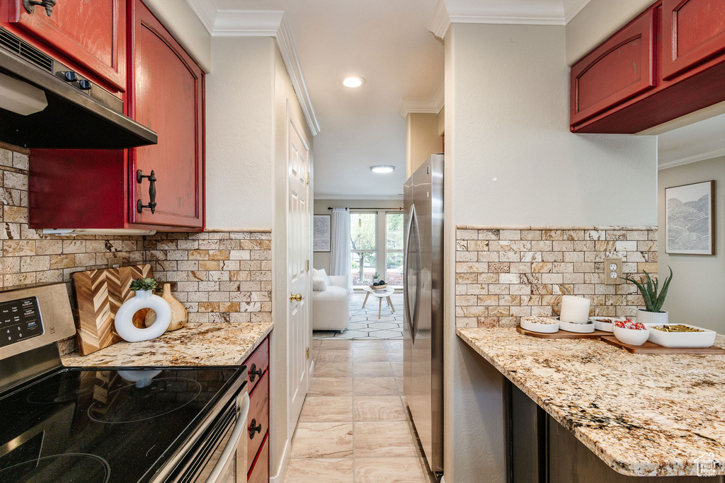 Kitchen with ornamental molding, stainless steel appliances, light tile floors, and light stone counters