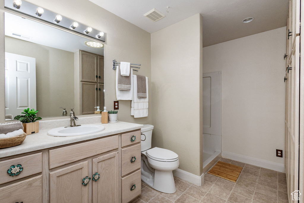 Bathroom featuring walk in shower, vanity, toilet, and tile flooring