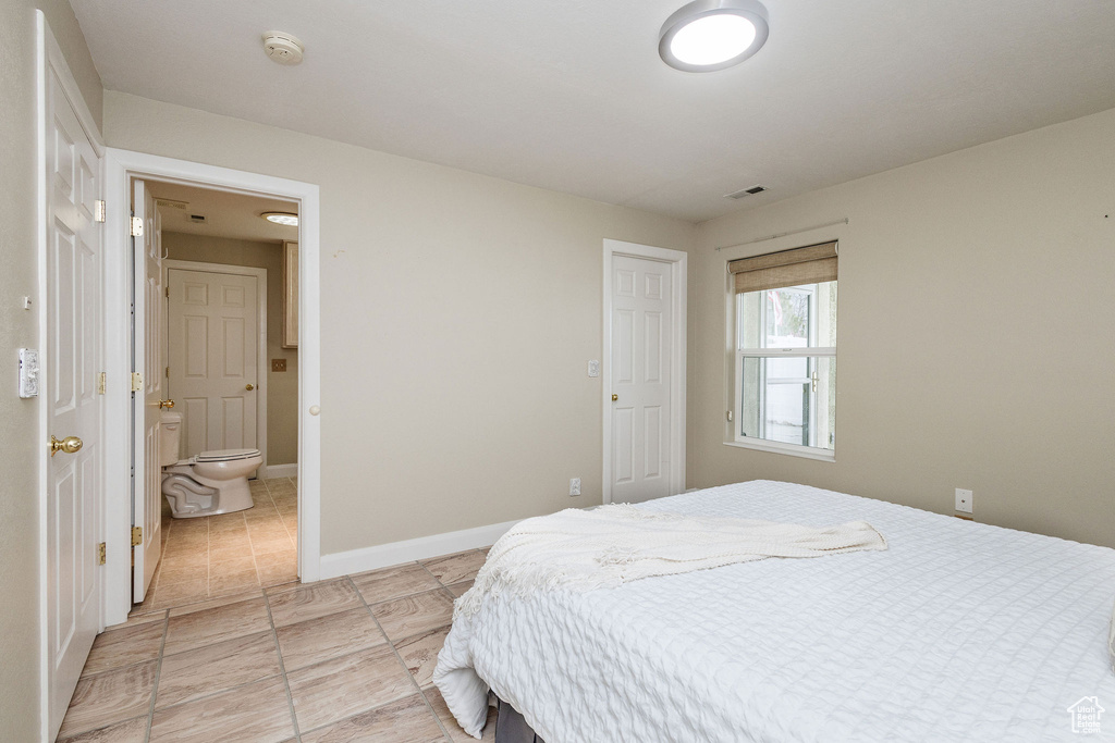 Bedroom with ensuite bathroom and light tile floors