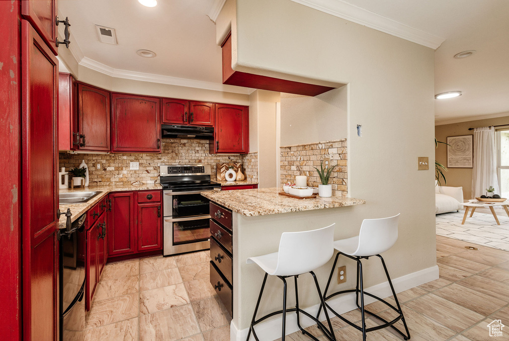 Kitchen featuring light tile flooring, backsplash, light stone counters, and stainless steel electric stove