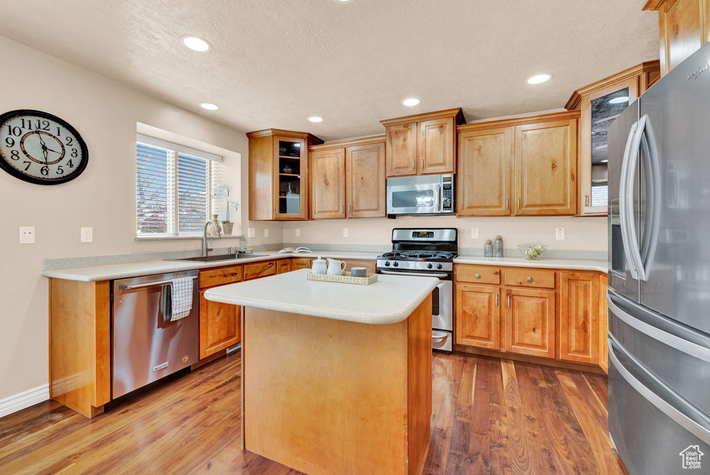 Kitchen featuring a center island, sink, appliances with stainless steel finishes, and hardwood / wood-style floors