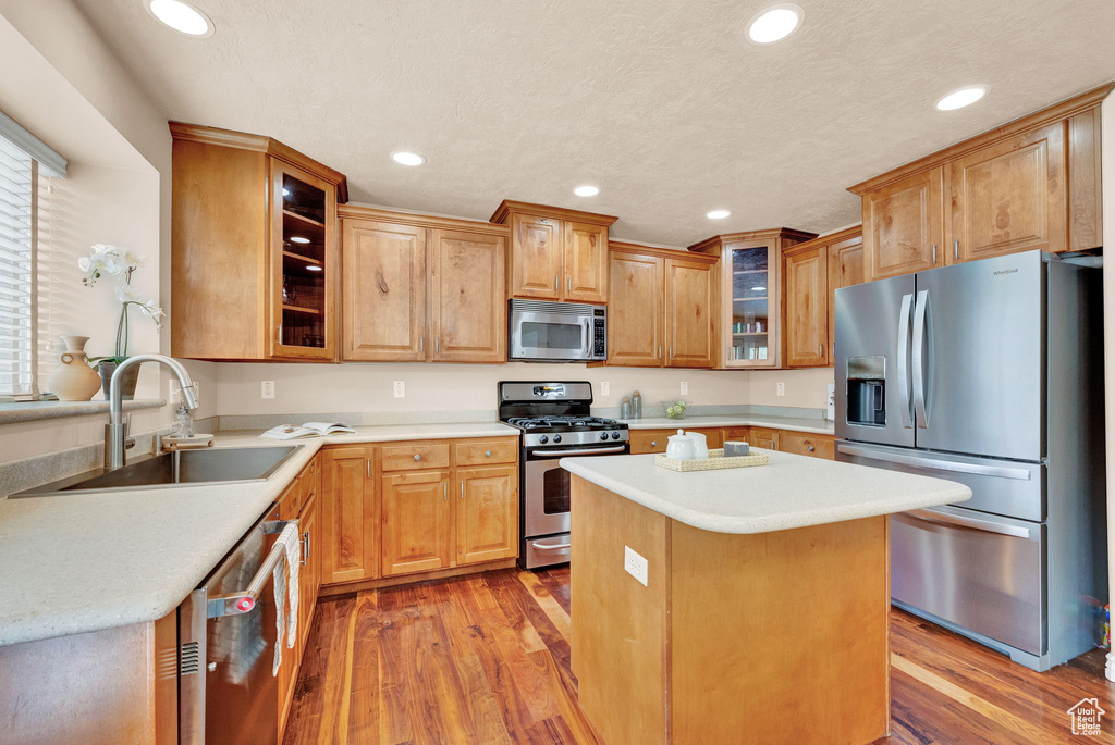 Kitchen featuring light hardwood / wood-style floors, appliances with stainless steel finishes, a kitchen island, and sink