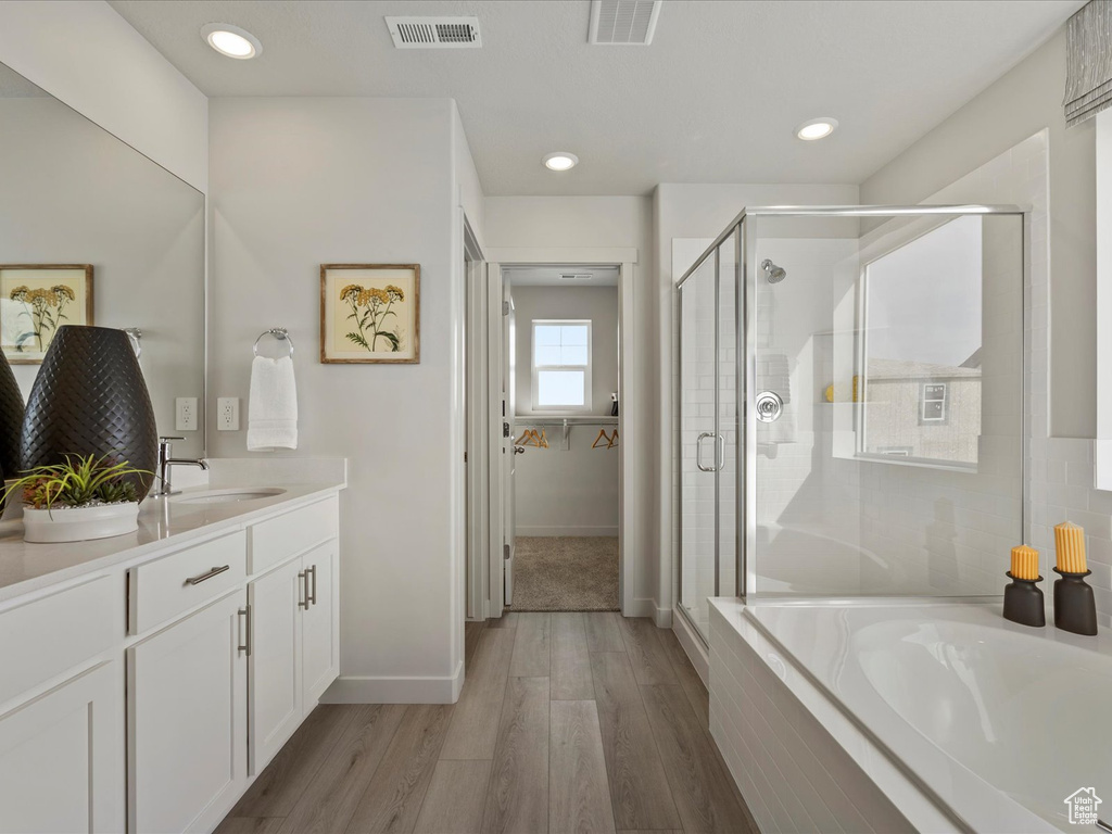 Bathroom featuring hardwood / wood-style flooring, independent shower and bath, and vanity