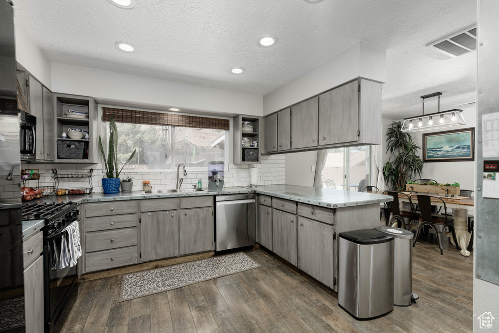 Kitchen featuring sink, tasteful backsplash, stainless steel appliances, dark hardwood / wood-style floors, and kitchen peninsula