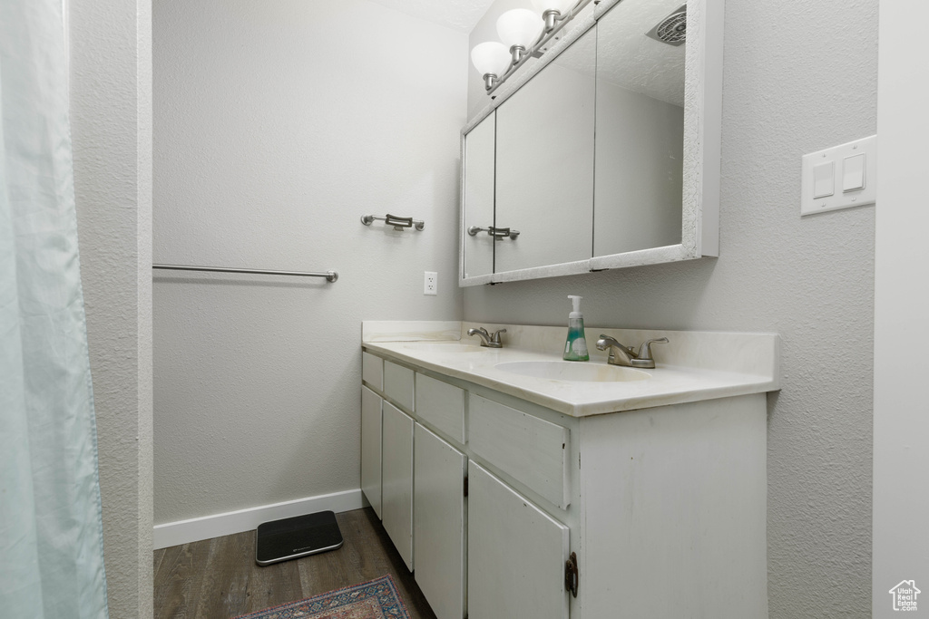 Bathroom featuring hardwood / wood-style floors, double vanity, and a textured ceiling