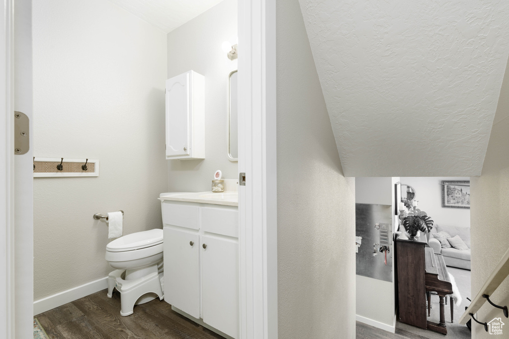 Bathroom with lofted ceiling, vanity, toilet, and hardwood / wood-style flooring