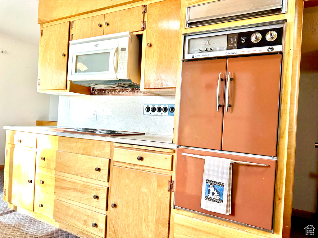 Kitchen featuring backsplash, gas cooktop, light hardwood / wood-style floors, and fridge
