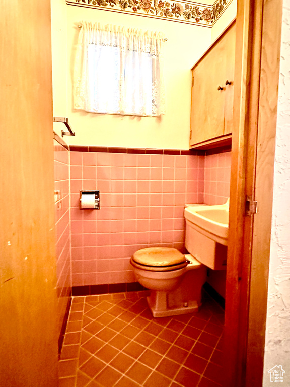 Bathroom featuring toilet, tile floors, and tile walls