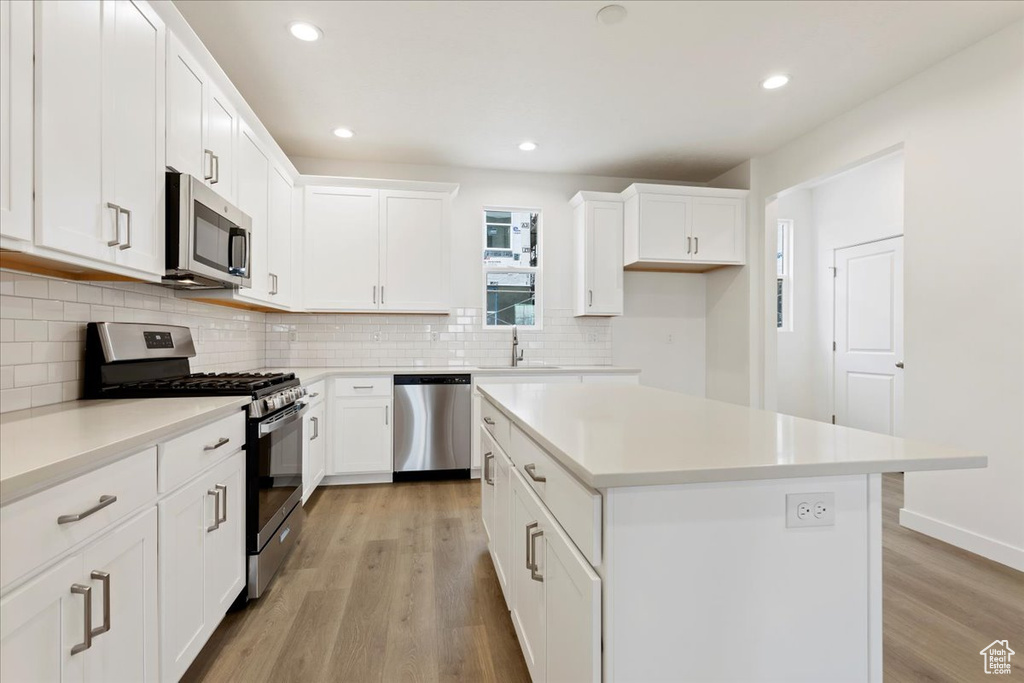 Kitchen featuring a center island, white cabinetry, light wood-type flooring, and stainless steel appliances