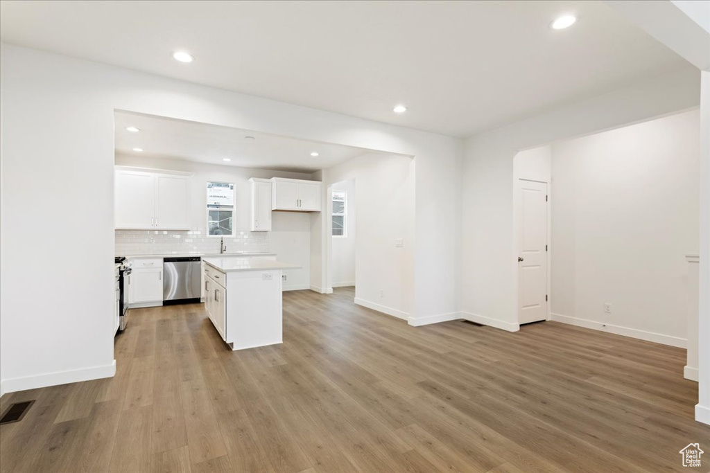 Kitchen with a center island, white cabinets, light wood-type flooring, and dishwasher