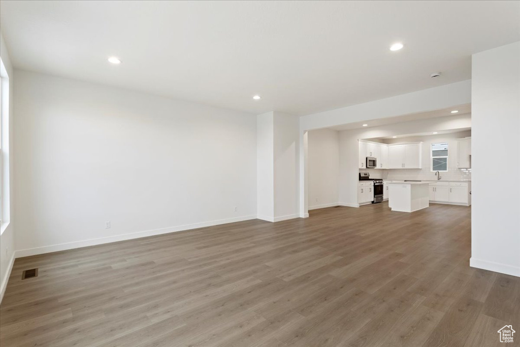 Unfurnished living room with hardwood / wood-style floors and sink