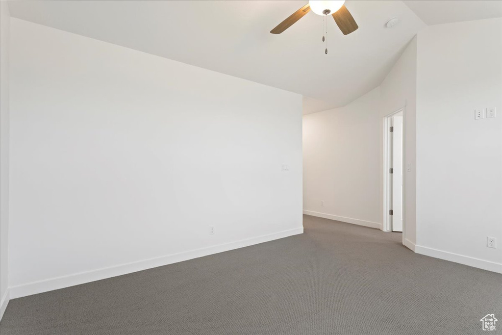 Unfurnished room with vaulted ceiling, dark carpet, and ceiling fan